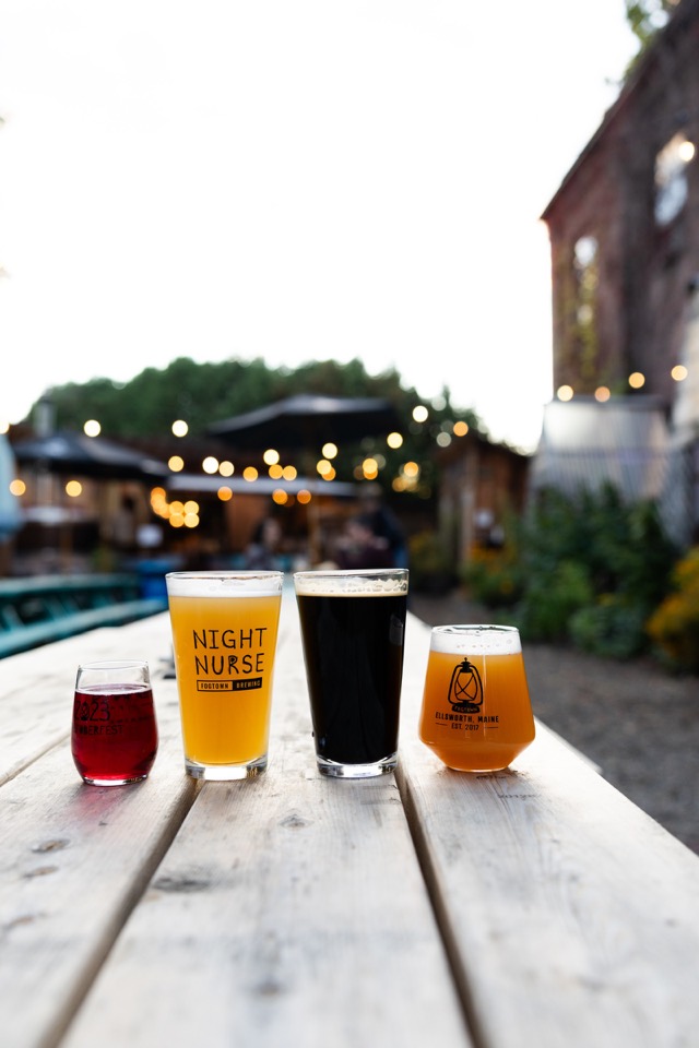 Four pours lined up on a picnic table in the beer garden, from ruby to stout black