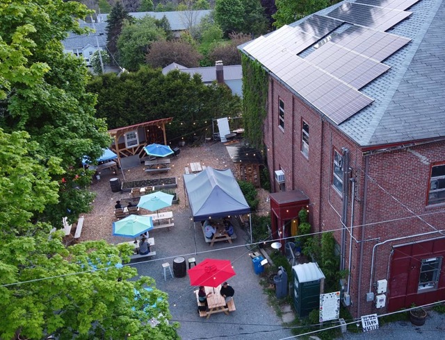 Aerial view of the brick brewery with rooftop solar panels and the beer garden beside it