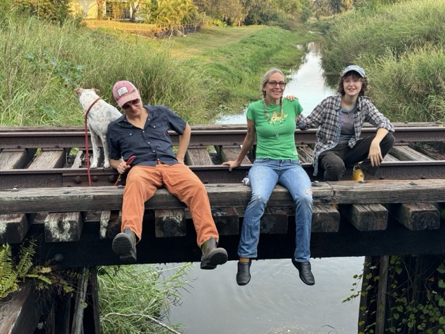 Hymn for Her sitting on a wooden bridge with a white dog