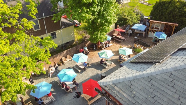 Aerial view of the beer garden’s blue umbrellas and tables beside the brewery roof