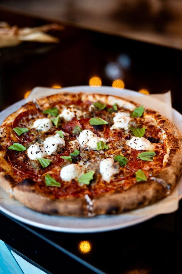 Wood-fired pizza with dollops of fresh mozzarella and basil